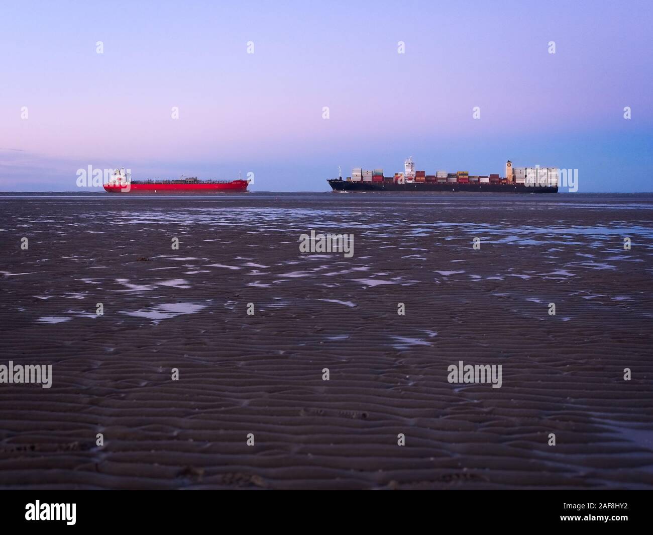 Due navi passando la bocca del fiume Elb in diverse direzioni vicino Otterndorf a bassa marea del mare di Wadden davanti a una bella sk pastello Foto Stock