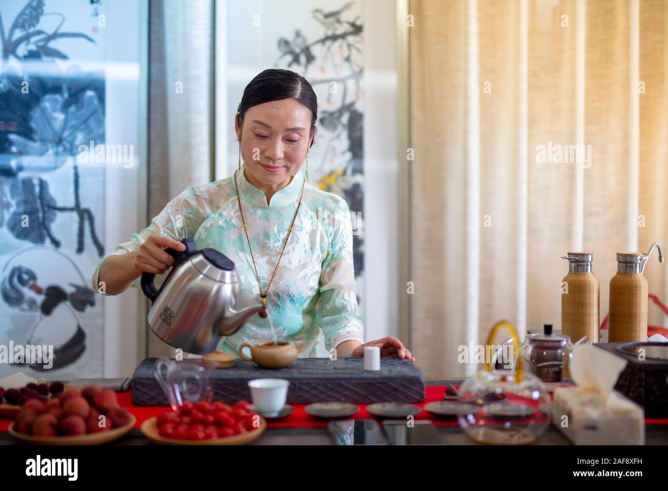 Una donna in abito tradizionale che fa il tè con il metodo tradizionale cinese utilizzando un tradizionale Yixing ware argilla viola teapot, Yixing, Cina Foto Stock