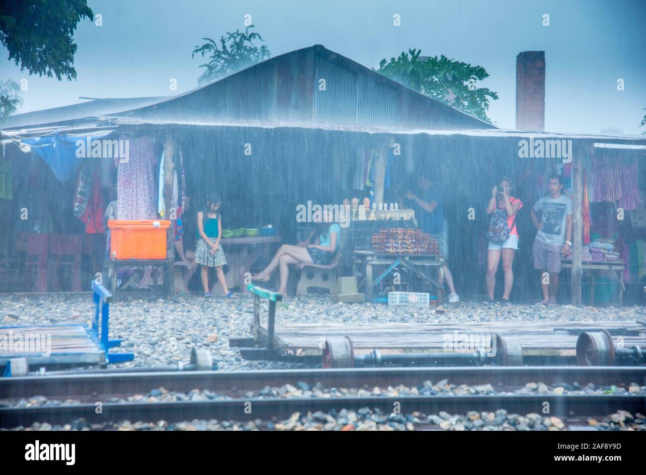 Turisti che si rifugiano dalla pioggia pesante al treno di bambù o stazione ferroviaria di norry costruita dalla gente locale durante la guerra civile, vicino a Battambang, Cambogia Foto Stock