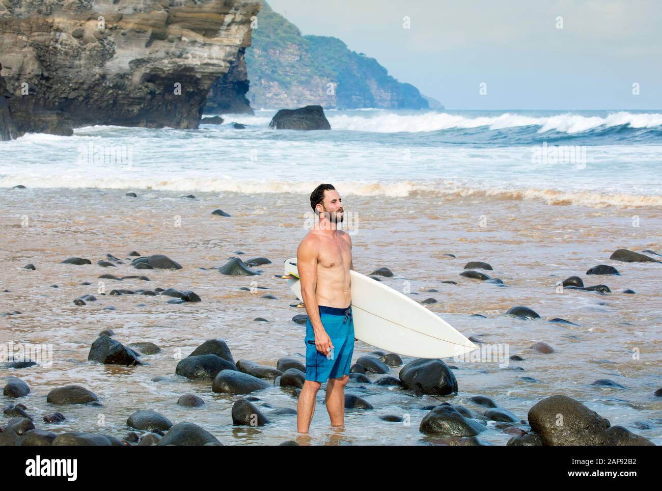 Un giovane maschio surfer su un Pacific Coast Beach in El Salvador, America Centrale Foto Stock