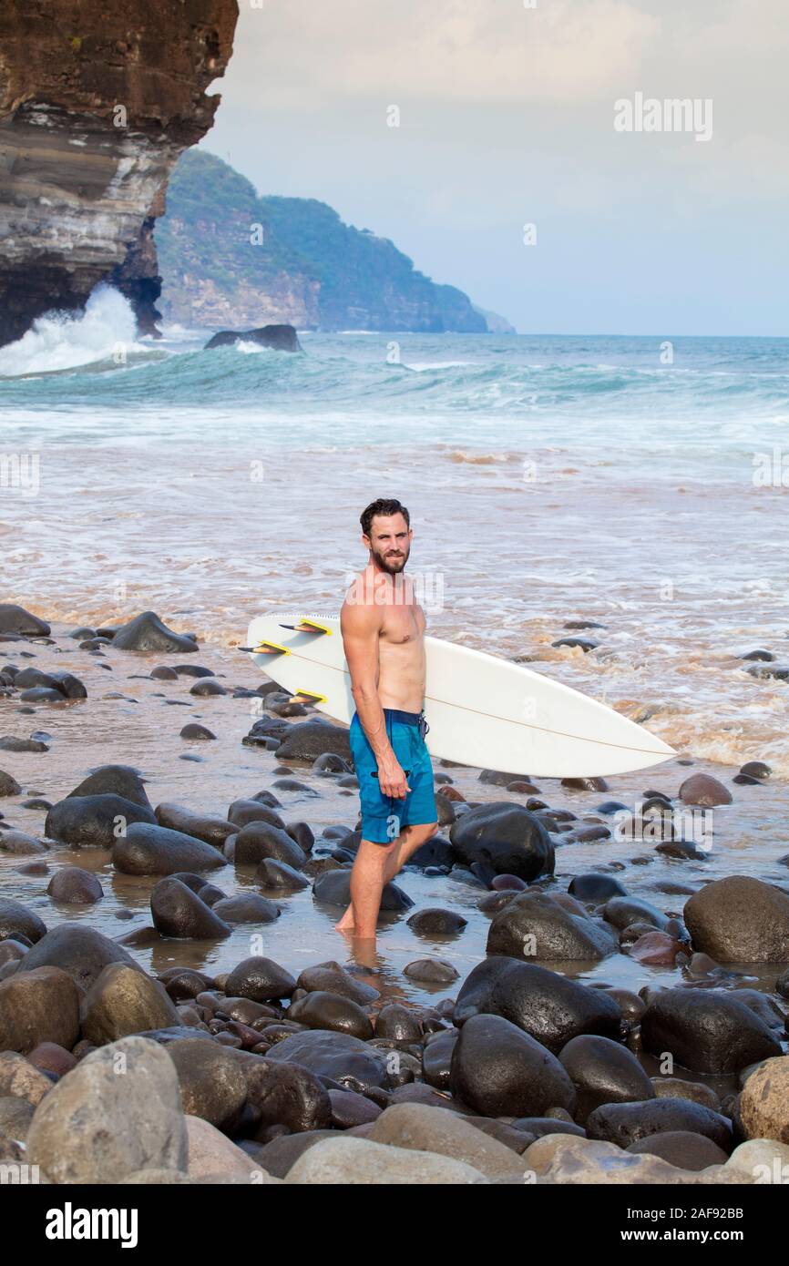 Un giovane maschio surfer su un Pacific Coast Beach in El Salvador, America Centrale Foto Stock