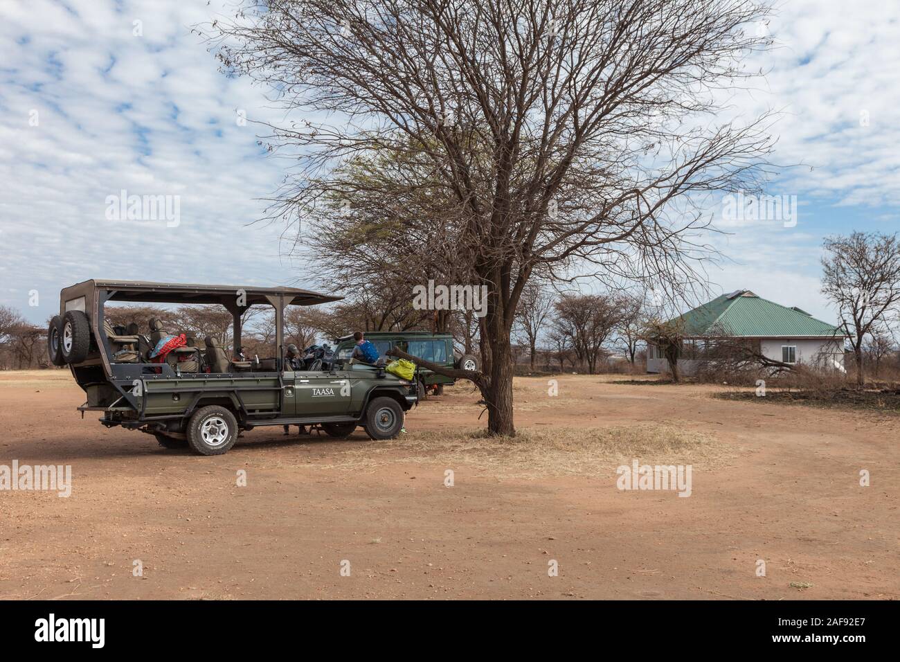 Tanzania. Gioco guidare il veicolo in attesa al lobo pista di atterraggio per aerei, Serengeti National Park. Sala di attesa sulla destra. Foto Stock