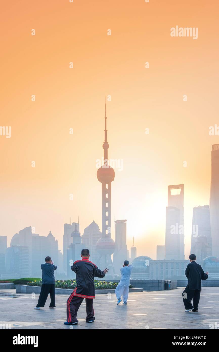 La gente del posto facendo Tai Chi all'alba contro il Pudong e la skyline di Shanghai, Cina Foto Stock