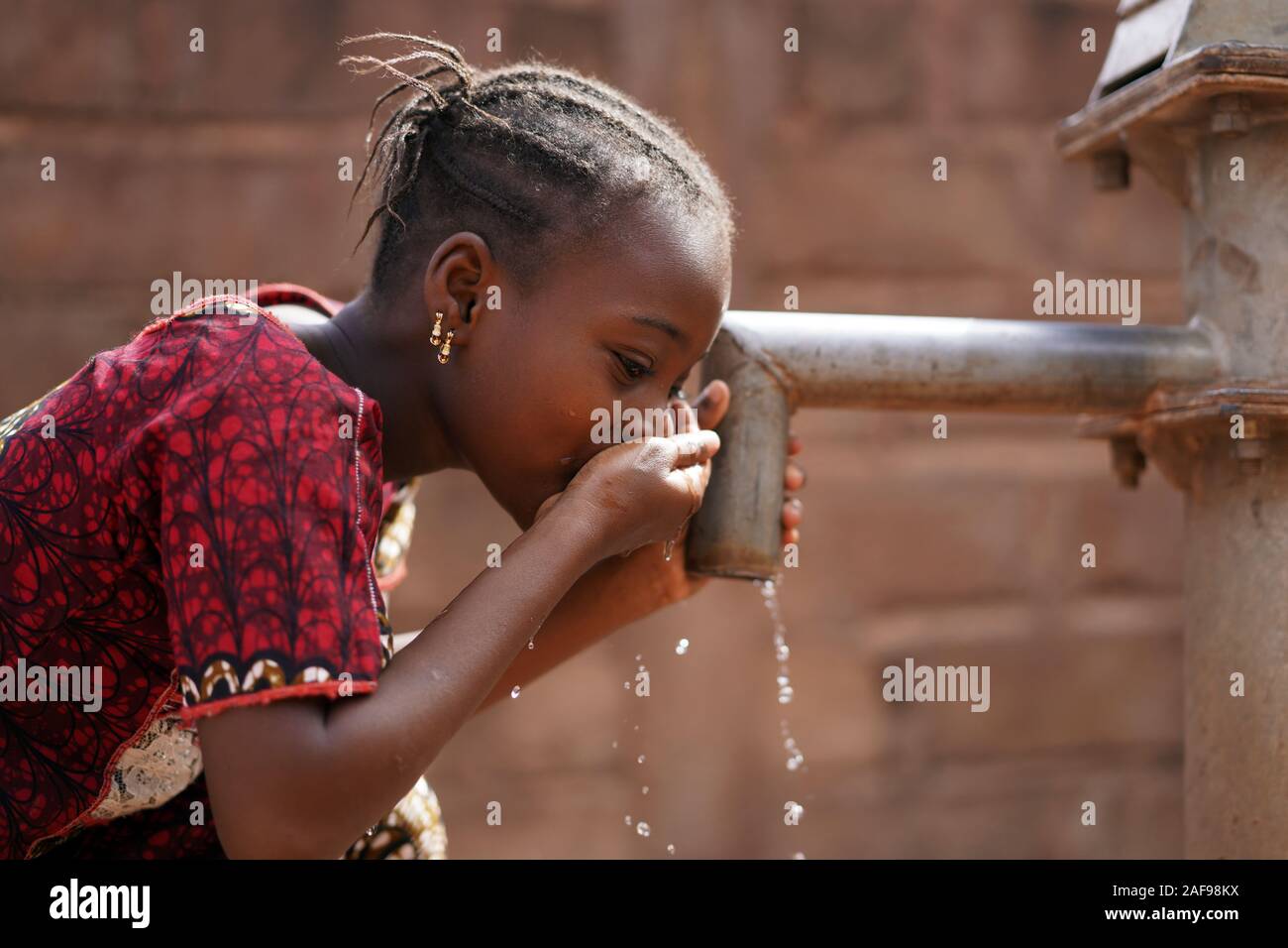 Primo piano di African Black Girl Bere acqua potabile all'aperto Foto Stock