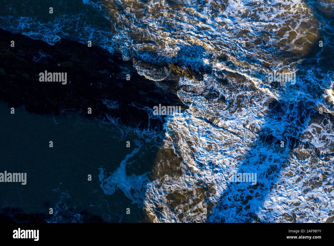 Le onde si infrangono contro la costa rocciosa di St Andrews Scozia. Immagine di sfondo astratta perfetta. Foto Stock