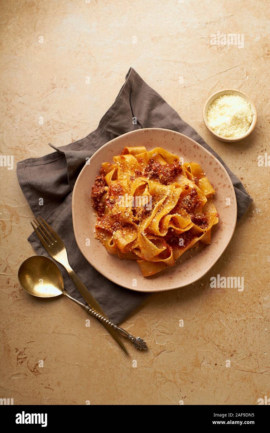 Flatlay con la classica pasta cotta bolognese con papardelle e partite di formaggio parmigiano Foto Stock