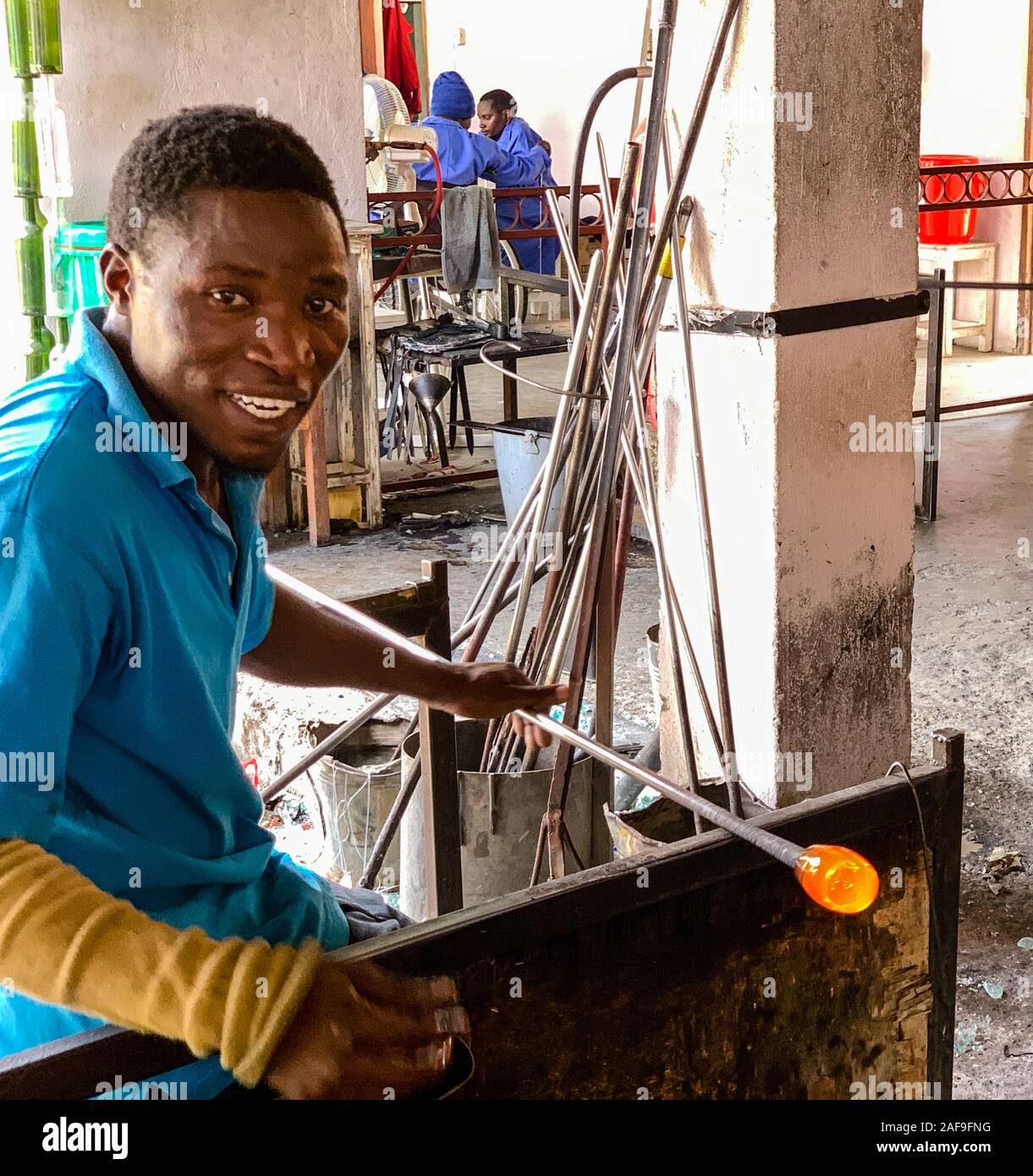 Tanzania. Arusha. Lavoratore disabile di sagomatura del vetro fuso per vetreria a Shanga, un centro artigianale che impiega i portatori di handicap. Foto Stock