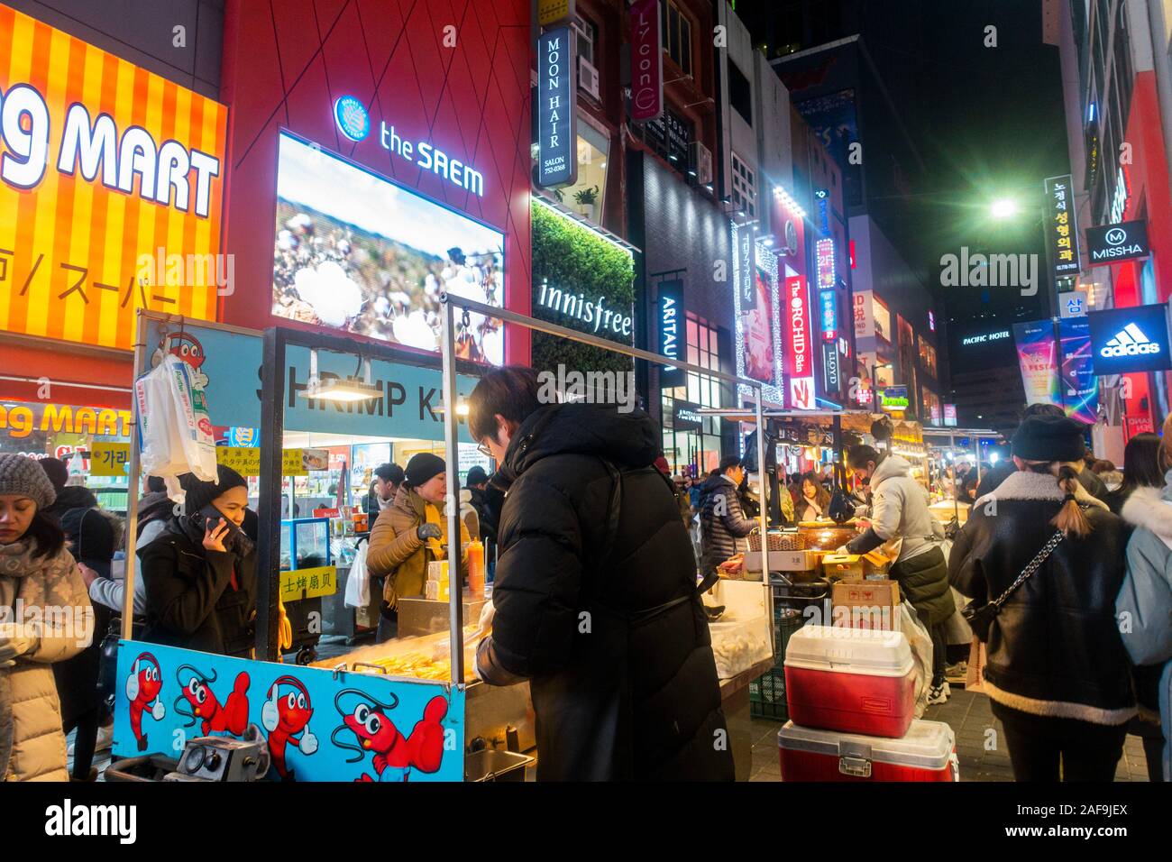 Seoul, Corea del Sud - 6 Dicembre 2019: a Myeongdong district a sera, il popolare sito per trattamenti estetici e di bellezza e negozi di cibo di strada. Foto Stock