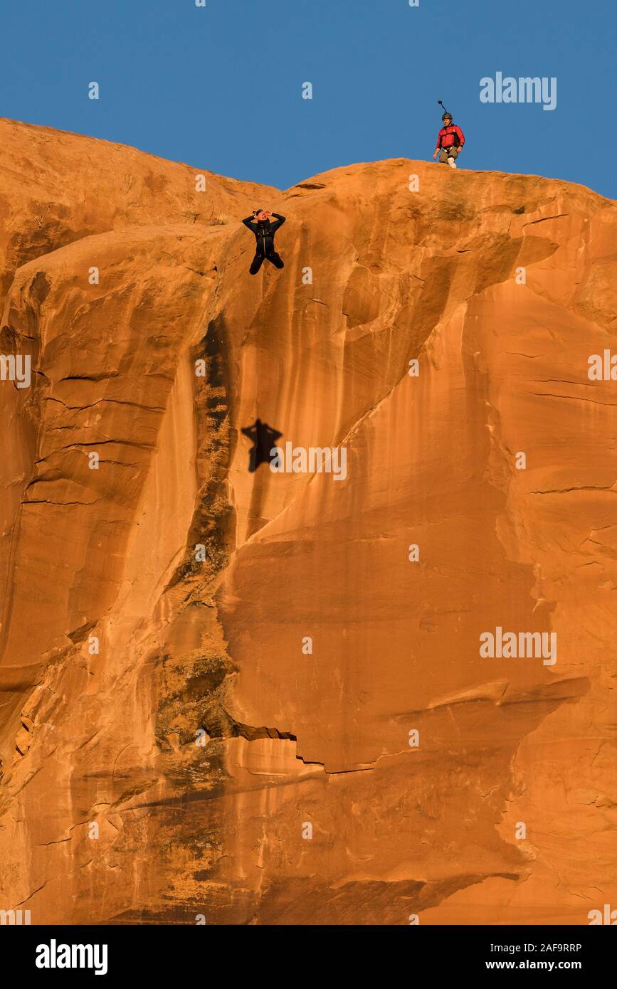 Un ponticello di base salta fuori dalla parte superiore del piede 400 faccia verticale dell'oggetto contrassegnato per la rimozione definitiva in Kane molle Canyon vicino a Moab, Utah. Nota la sua ombra sulla scogliera. Foto Stock