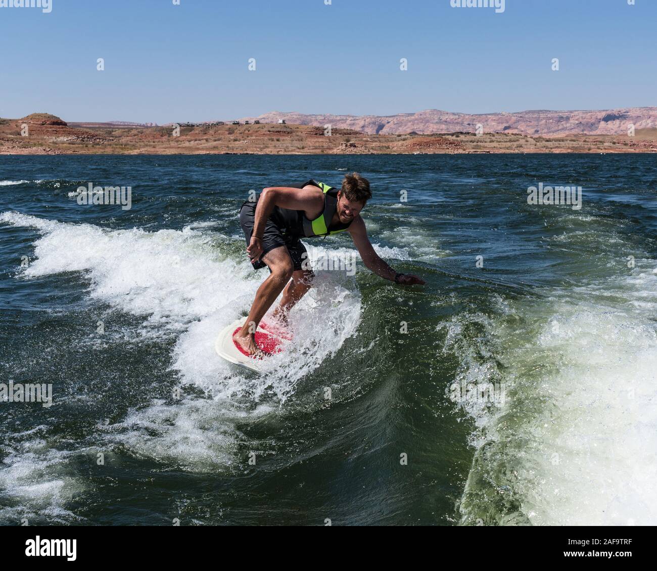 Un giovane uomo wake surf dietro una barca sul Lago Powell in Glen Canyon National Recreation Area nel sud dello Utah, Stati Uniti d'America. Foto Stock