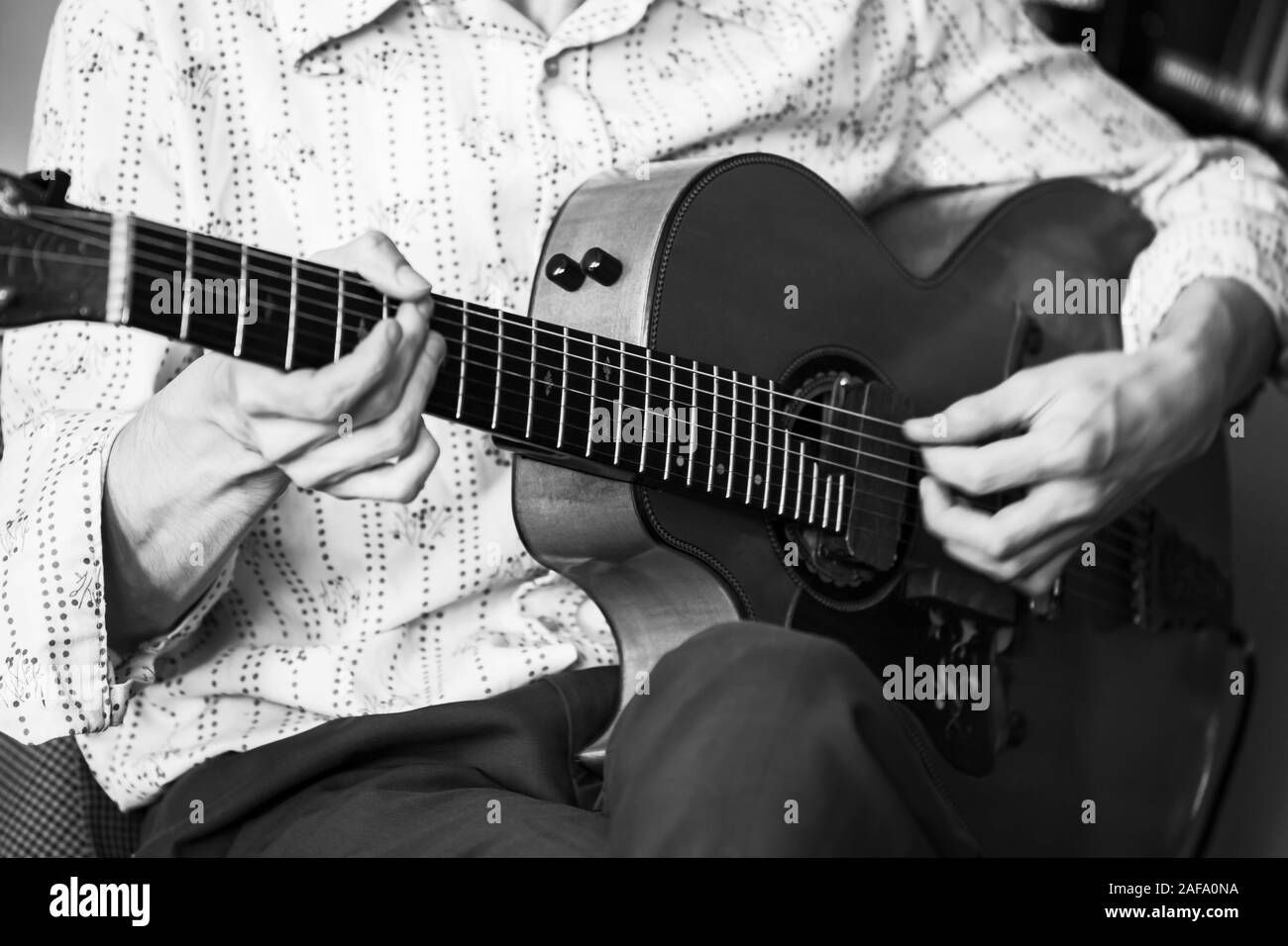 Una chitarra acustica player, close-up foto con morbida messa a fuoco selettiva. Retrò stilizzata in bianco e nero Foto Stock