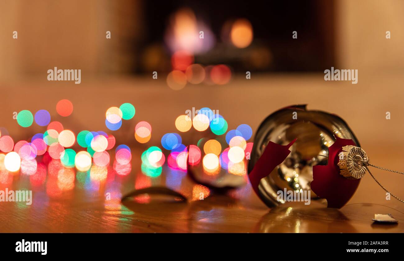 Decorazione per albero di Natale rotto. Vacanze di Natale decorazione, luci incandescente, blur caminetto a sfondo, riflessioni sul pianale in legno Foto Stock