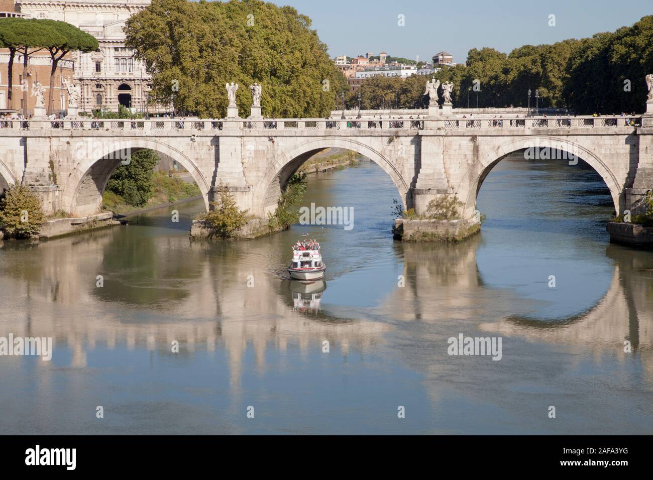 Una barca turistica passa sotto il Ponte Sant'Angelo vicino al Castel Sant'Angelo sul fiume Tevere a Roma Foto Stock