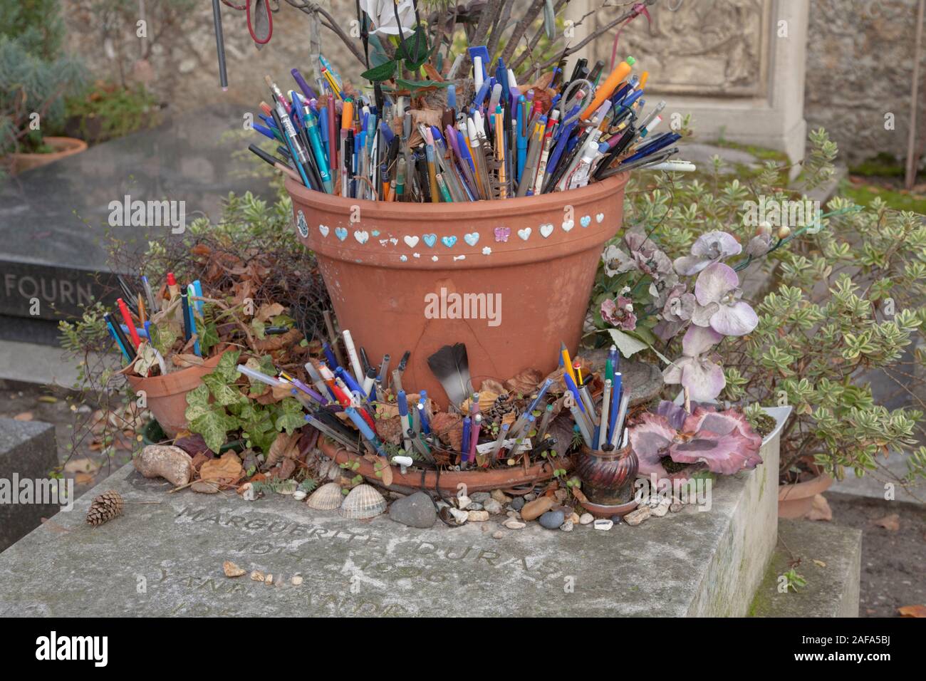 La tomba del romanziere francese e il drammaturgo Marguerite Duras nel cimitero di Montparnasse è coperto con le penne e i gettoni lasciati dai visitatori e appassionati Foto Stock