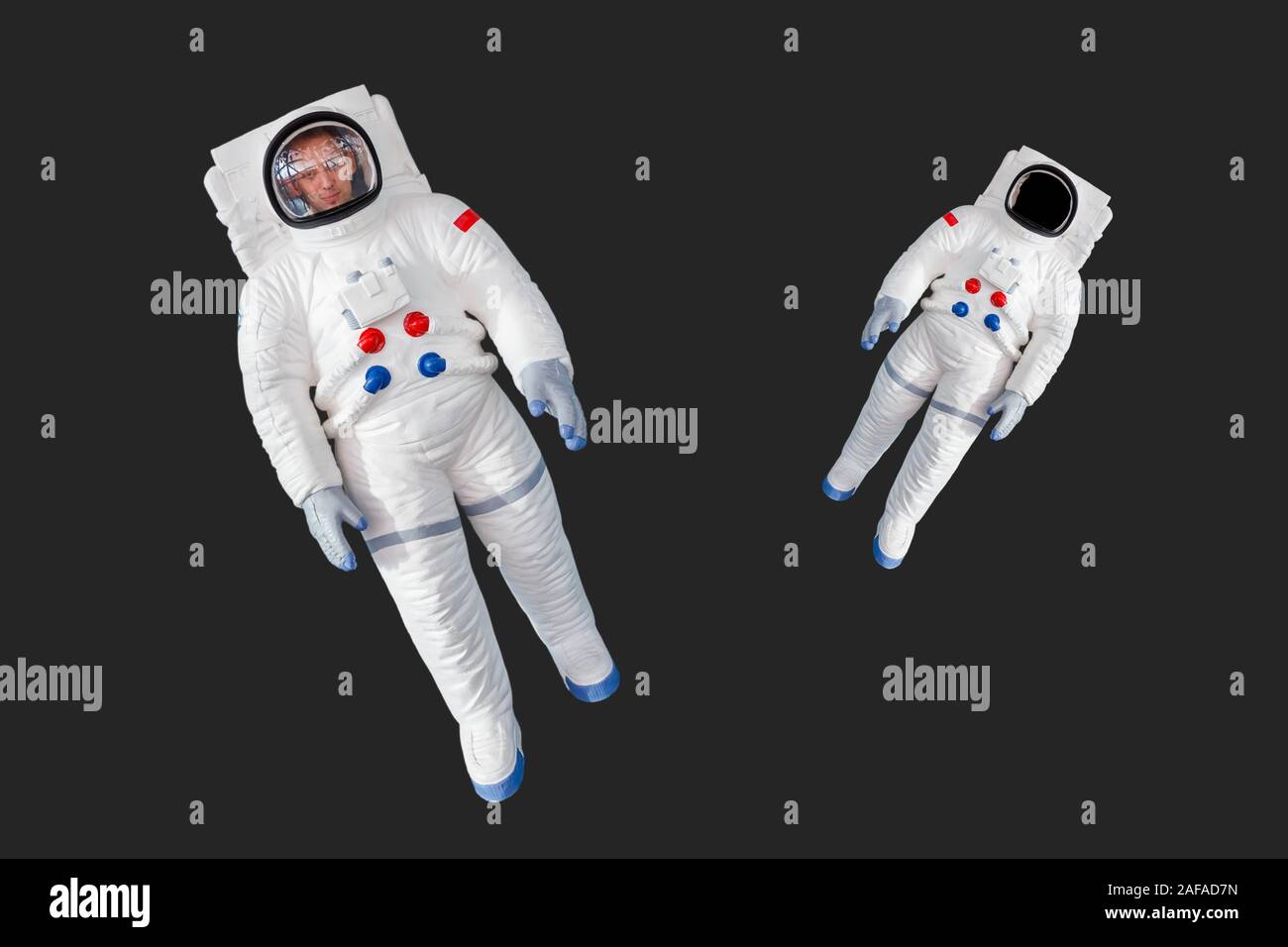 Due astronauti in tuta spaziale isolato su sfondo scuro con posto vuoto per il viso in uno di essi. Foto Stock