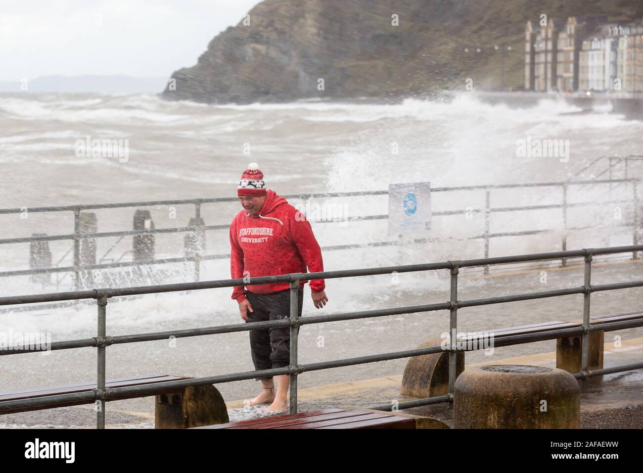 Aberystwyth, Ceredigion, Wales, Regno Unito. Xiv Dic, 2019. Regno Unito Meteo: Tre persone decidono di andare per una racchetta in passeggiata piscinetta per bambini come i venti forti e onde venire oltre il mare difese in Aberystwyth questa mattina. Credito: Ian Jones/Alamy Live News Foto Stock