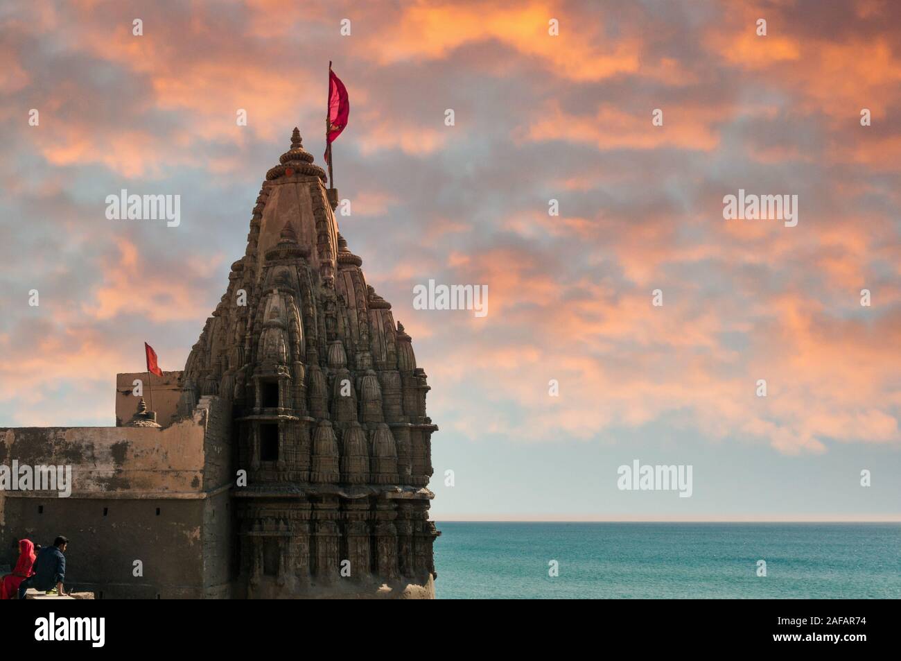 Tempio indù con pareti intagliato un alta guglia e bandiera sulla costa del mare blu Foto Stock