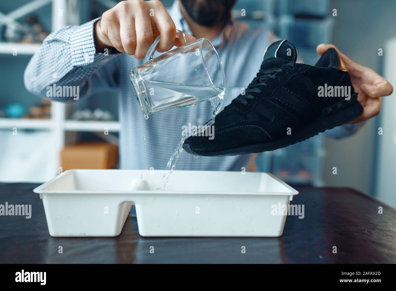 Calzolaio controllare le scarpe per la resistenza all'acqua Foto Stock