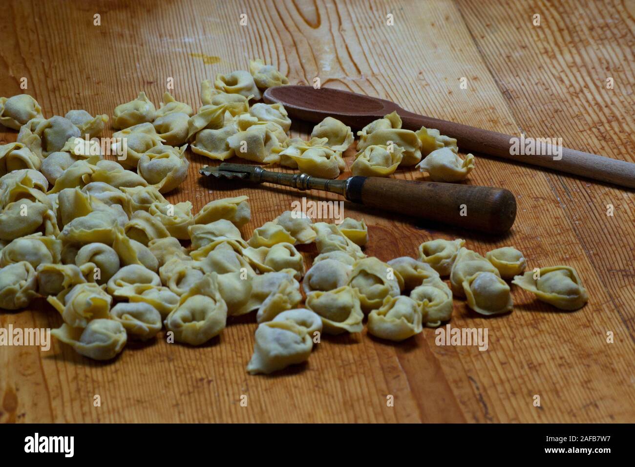 Fatte a mano e tortellini fatti in casa su di un legno scheda chopper. Prodotti tipici di Modena e Bologna, Emilia Romagna, Italia. Cibo tradizionale Foto Stock