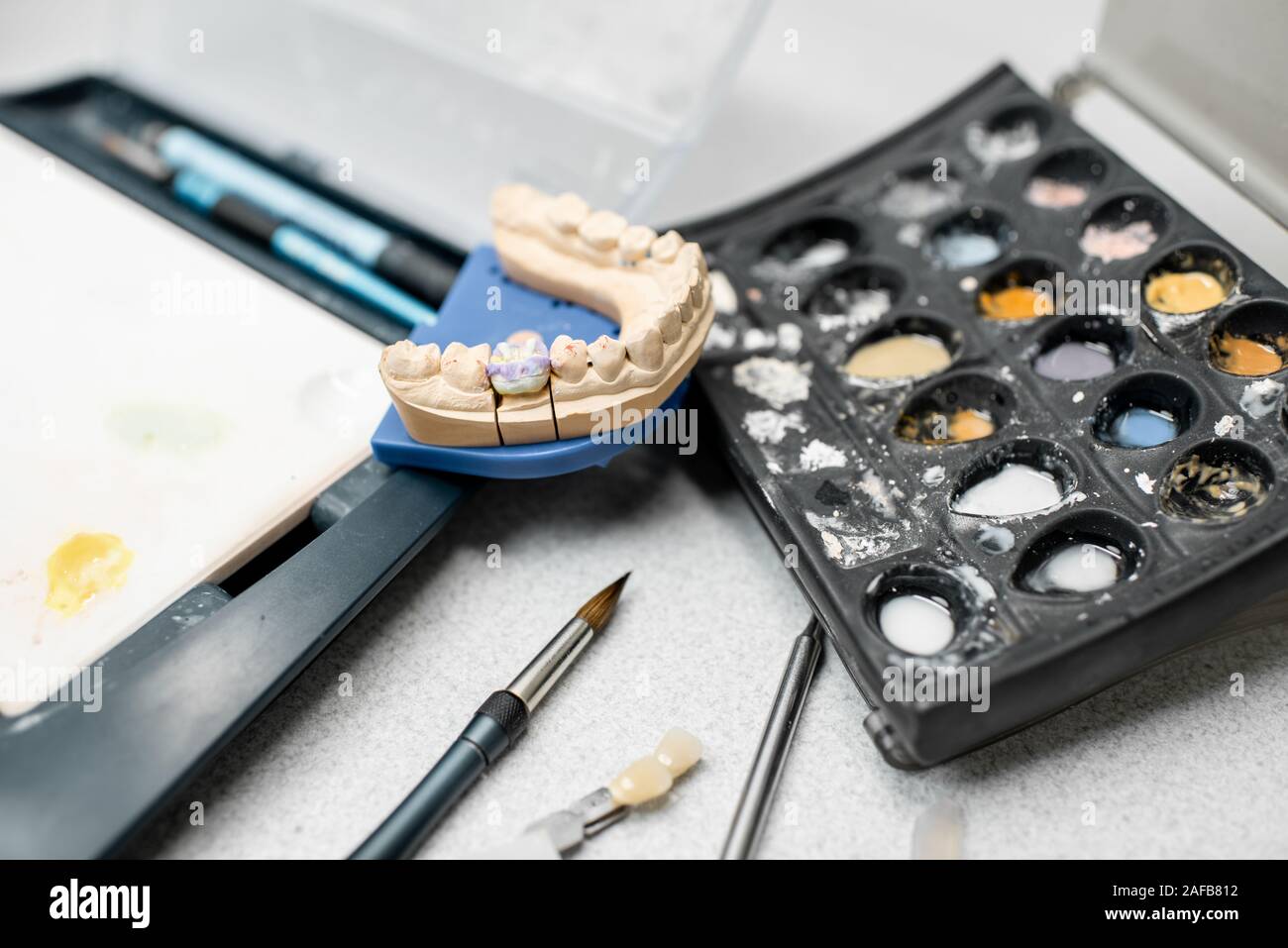 Colorate protesi dentale con una spazzola di vernice sul luogo di lavoro in laboratorio. Concetto di implantats producendo e arte dentale Foto Stock