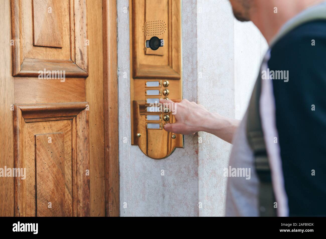 Close-up mano umana squilla il citofono per accedere all'interno della casa. Foto Stock
