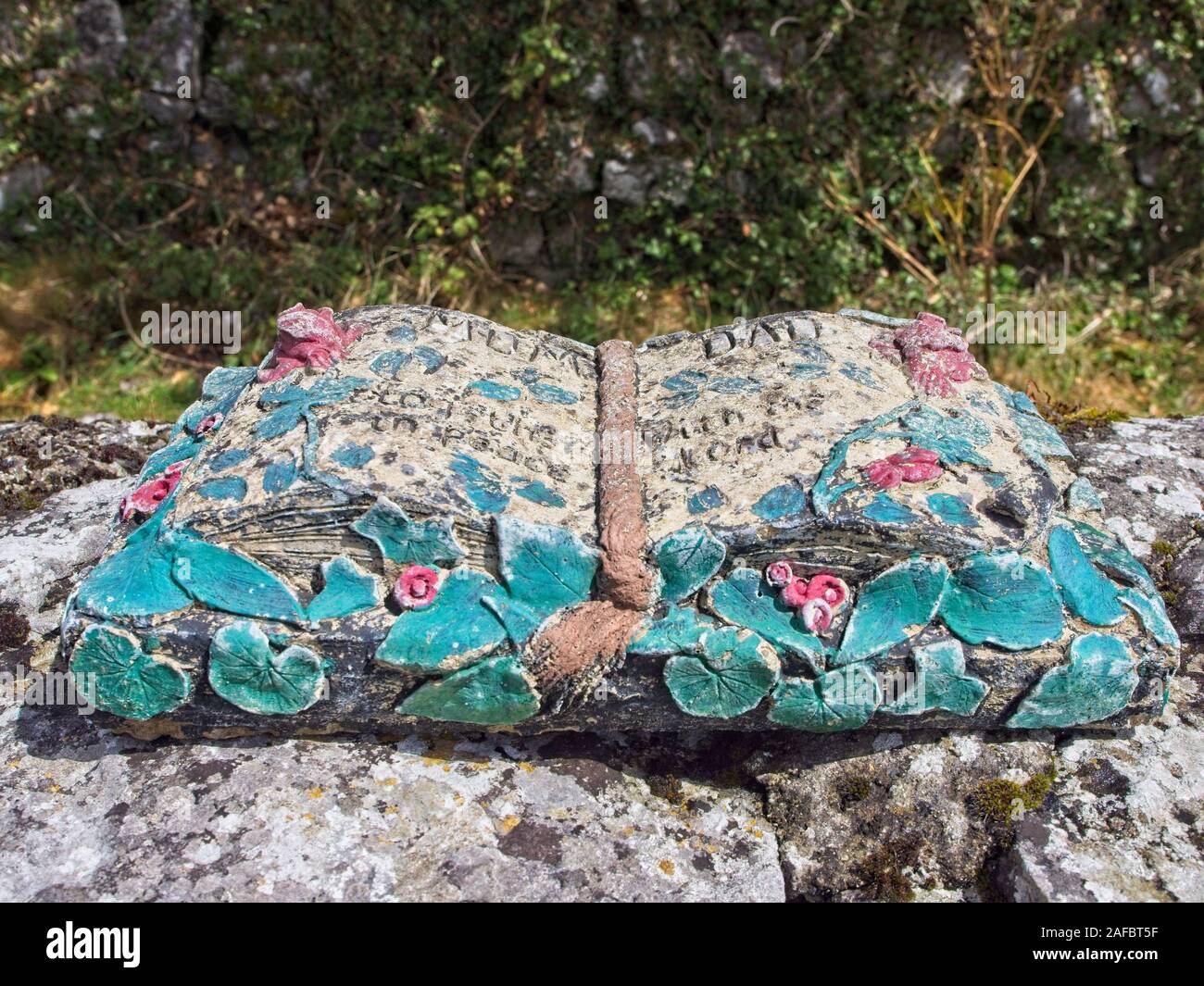 Una molto antica pietra scultura di un libro al cimitero storico di Corcomroe Abbey, aperto nel medio con ornamenti colorati che assomigliano a leafes e ro Foto Stock