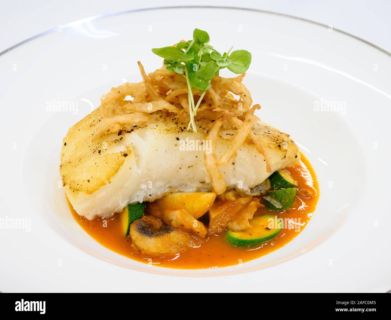 Ristorante Iguana entree Robalo Chileno (Mare cileno Bass con patate, zucchini, chorizo, funghi, un tocco di Cile e condito con cipolla croccante); Foto Stock