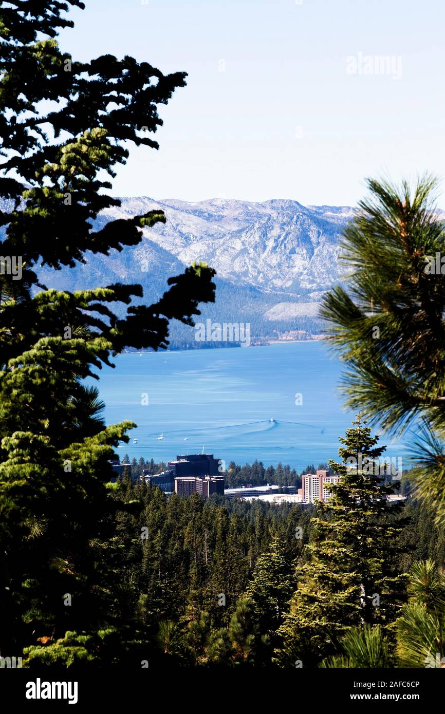 South Lake Tahoe e linea di Stato di Nevada Visto dalle colline attraverso gli alberi con le montagne e gli edifici Foto Stock