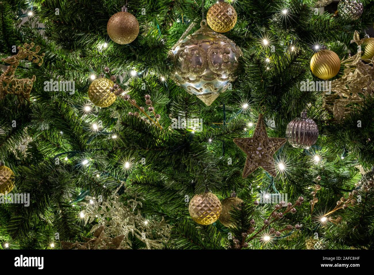 Dettagli di un albero di Natale con rami di albero appeso con una palla e stelle di ornamenti, nastri e giocattoli di Natale. Il concetto della tradizionale celebrazione. Foto Stock