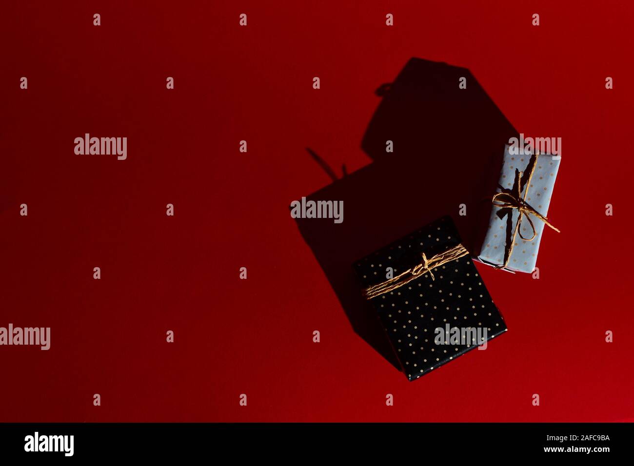 Confezioni regalo legati con corda artigianale su uno sfondo di colore rosso. Disco ombre di luce cruda. Posto per il testo Foto Stock