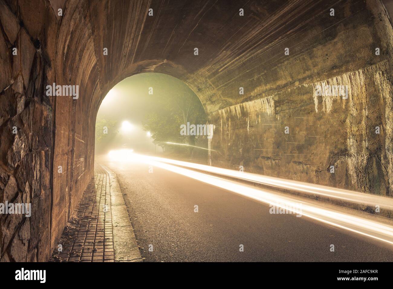 Il Tunnel. Vie di uscita con spooky foschia e la nebbia di notte con sentieri loght dall'auto. Foto Stock