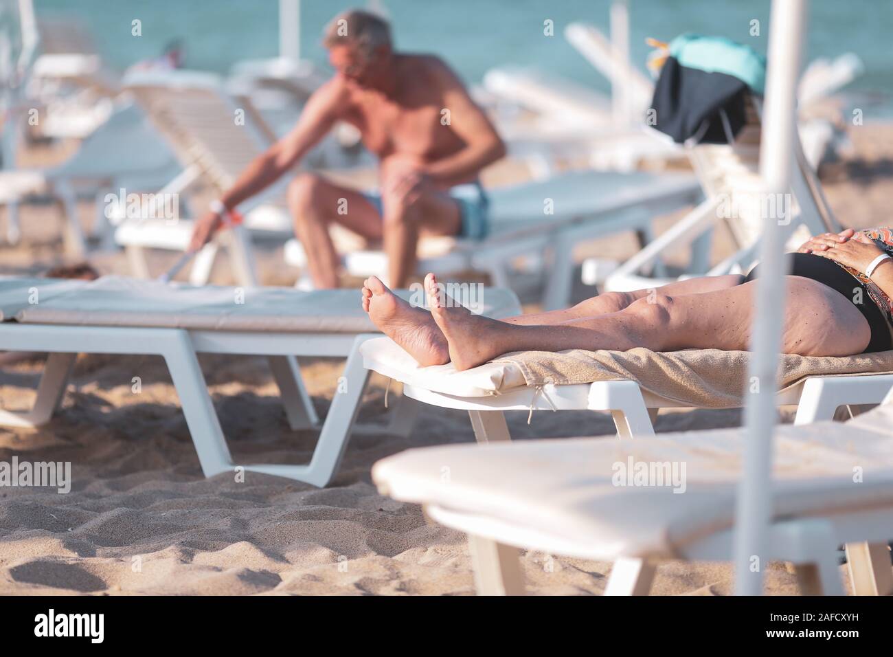 Le persone anziane godendo di prendere il sole sulla spiaggia durante le loro vacanze estive Foto Stock
