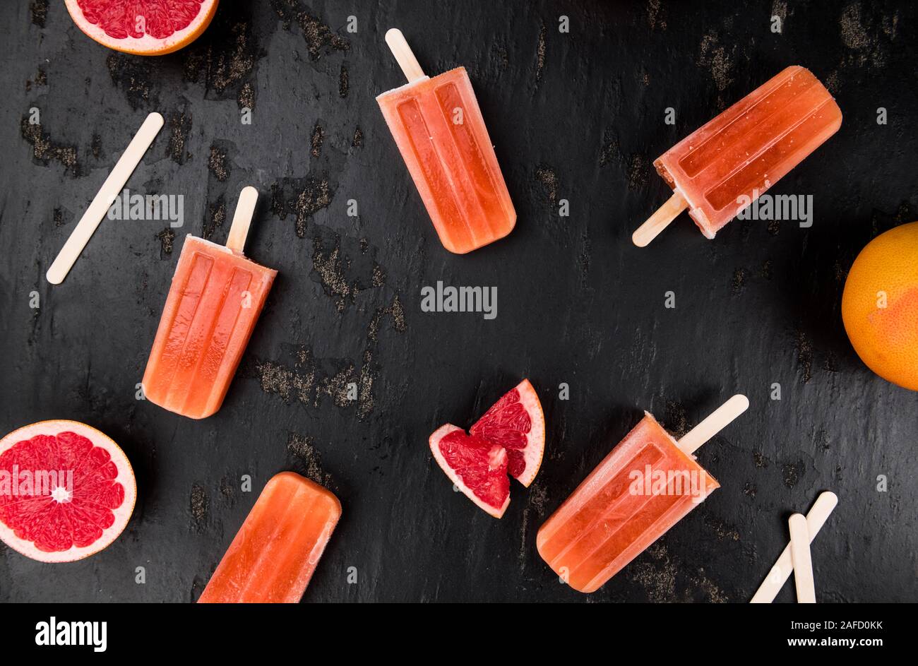 Alcuni fatti in casa Popsicles di pompelmo (con alcuni frutti freschi) come close-up shot (messa a fuoco selettiva) Foto Stock