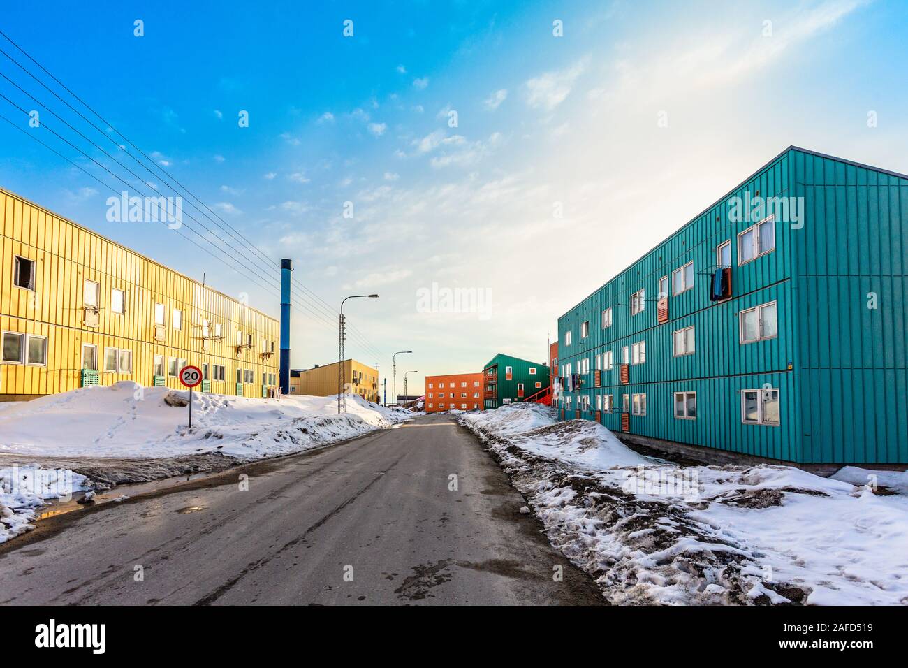 Strada fangosa con neve e blocchi vivente con lunghi edifici bassi nella città di Ilulissat in Groenlandia Foto Stock