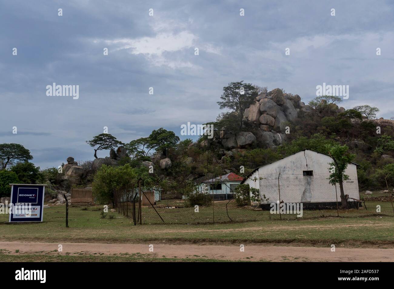 Manicaland, Zimbabwe orientale. Un annuncio per il servizio wireless Econet sulle terre di una piccola fattoria sotto una fomazione di granito, noto come Kopje. Econet è la più grande rete wireless dello Zimbabwe e offre anche un servizio di pagamento telefonico, Ecofin. Nel giugno 2020 il governo dello Zimbabwe ha dichiarato di voler chiudere Ecofin, sostenendo che l'azienda ha utilizzato un rapporto di cambio non ufficiale e ha quindi contribuito all'inflazione nel paese. Questo passo avrà gravi risultati, in quanto Ecofin sostituisce il conto bancario di molte delle popolazioni povere del paese. Foto Stock