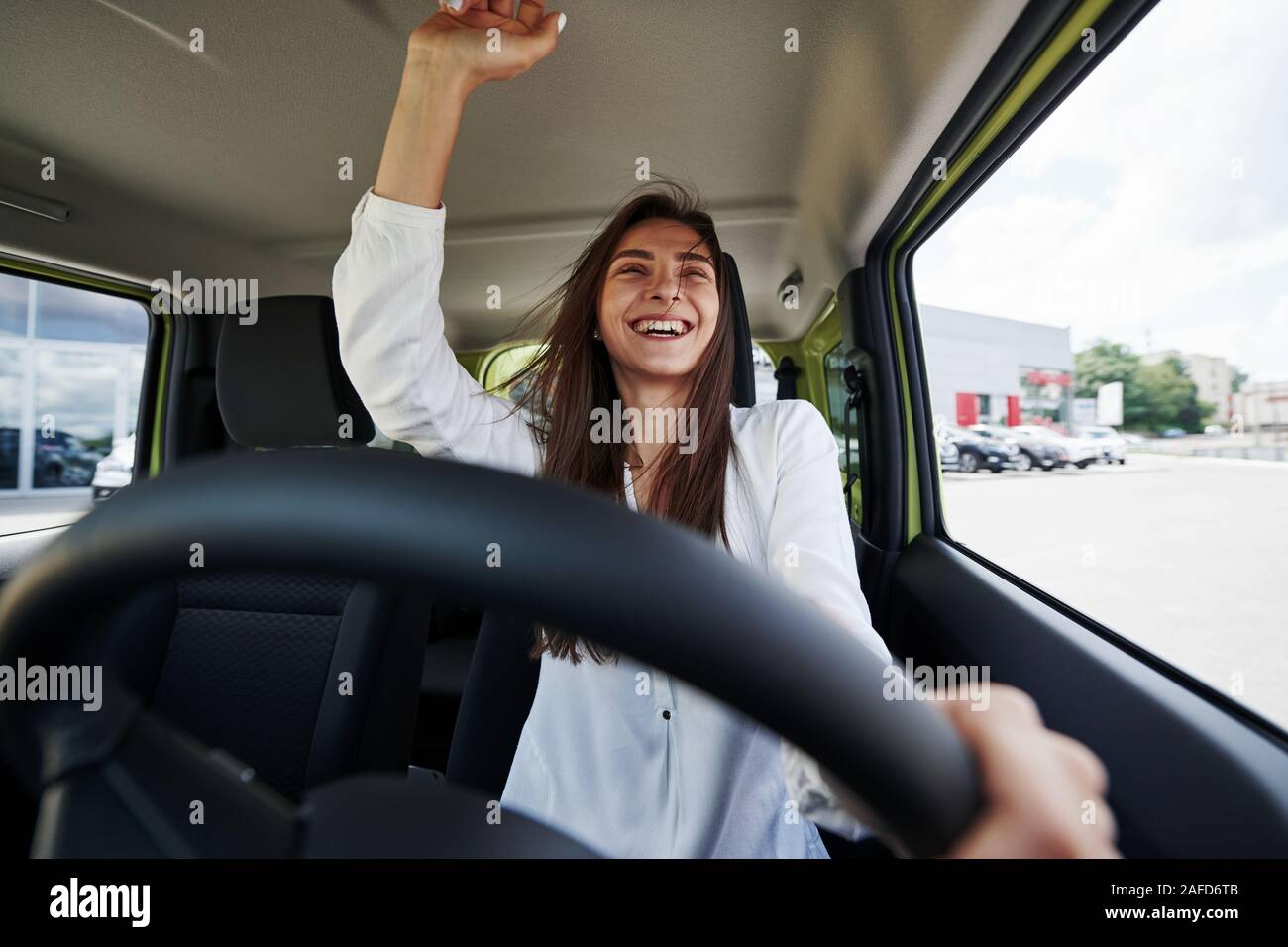 Felice proprietario. Vista frontale della donna che aziona nuove e moderne auto in città Foto Stock