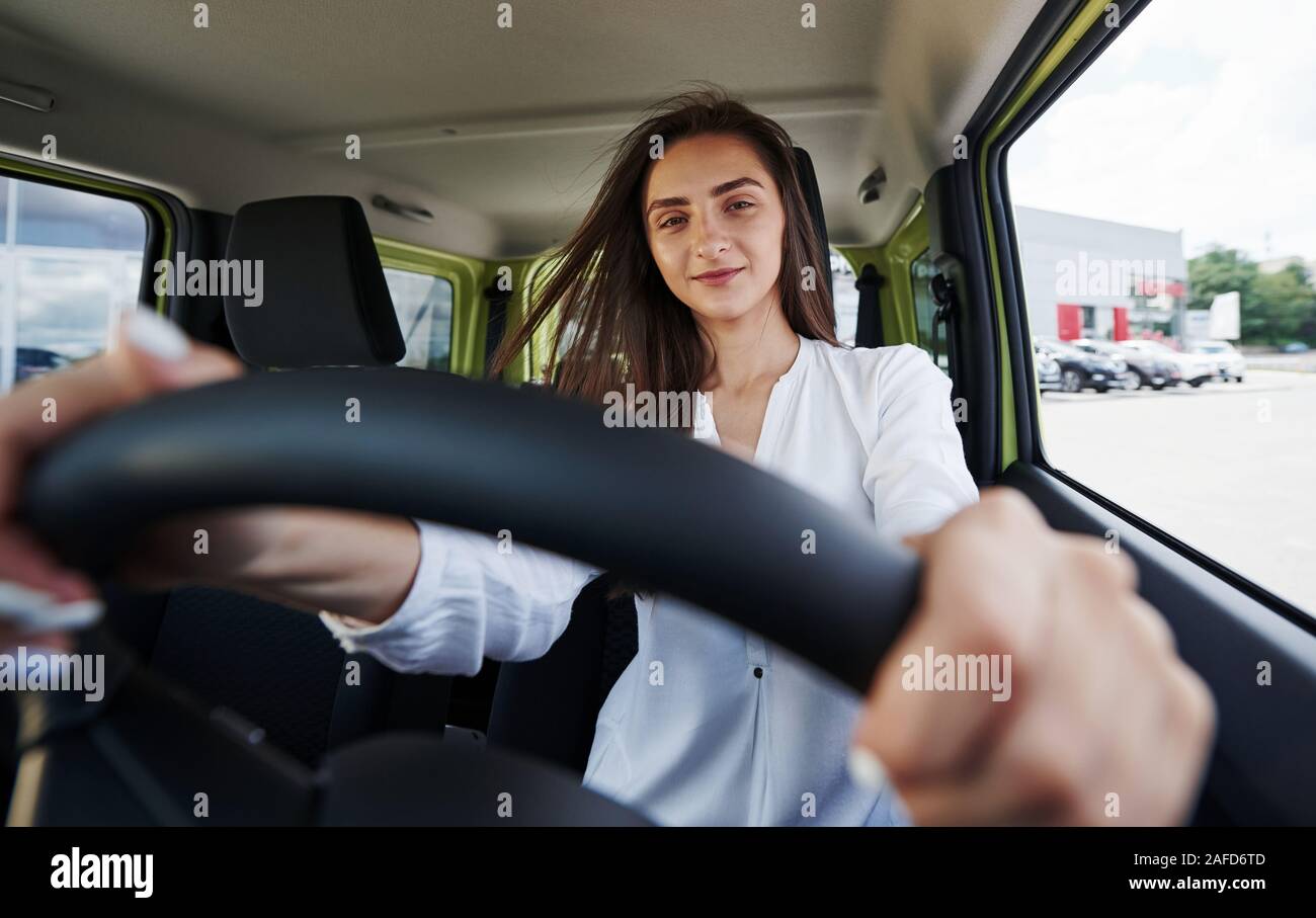 Felice proprietario. Vista frontale della donna che aziona nuove e moderne auto in città Foto Stock