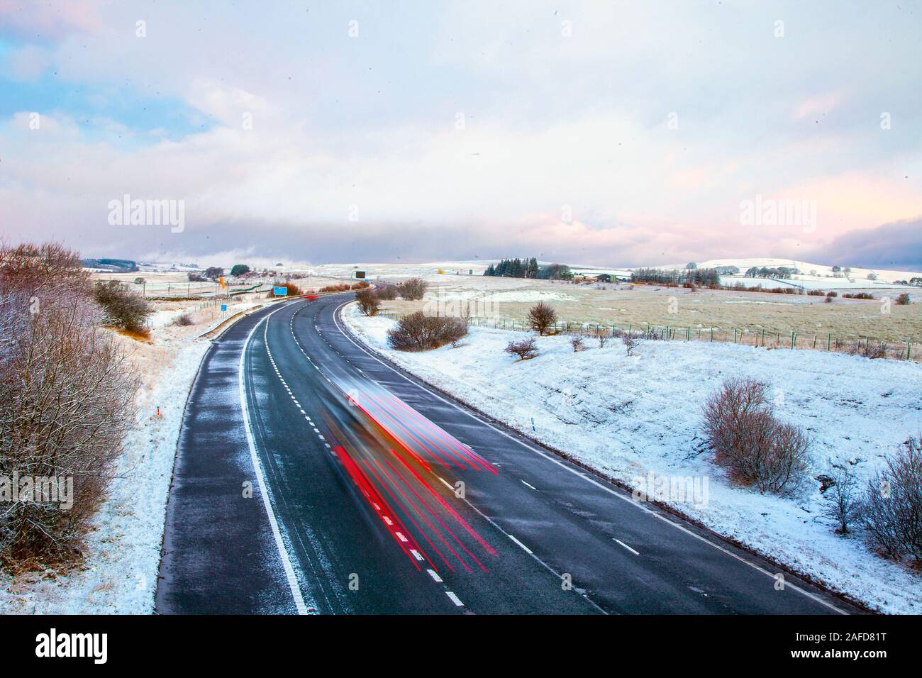 Tebay, Cumbria, Regno Unito. Il 15 dicembre, 2019. Sfumature sottili all'alba; la mattina presto il gelo e la bufera di neve che ricopre il Tebay paesaggio invernale come traffico di teste di Shap un rinomato freddo difficile la guida posto nella Westmorland Fells. Credito: MediaWorldImages/Alamy Live News Foto Stock