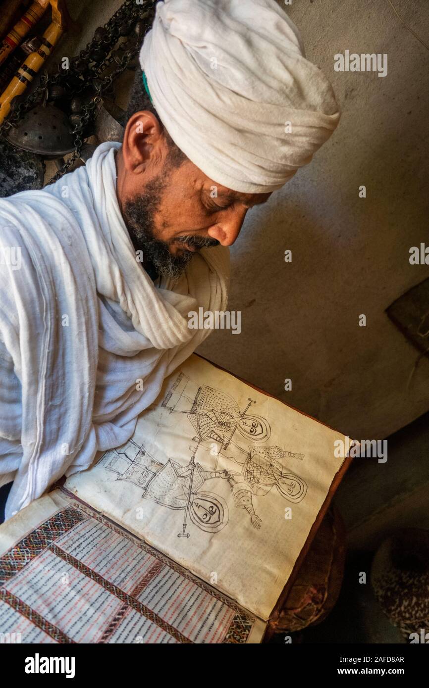 Etiopia, Tigray, Adwa, Yeha, sacerdote visualizzazione antico manoscritto illuminato con monocromatico disegno della linea dei sacerdoti con bastoni di preghiera Foto Stock