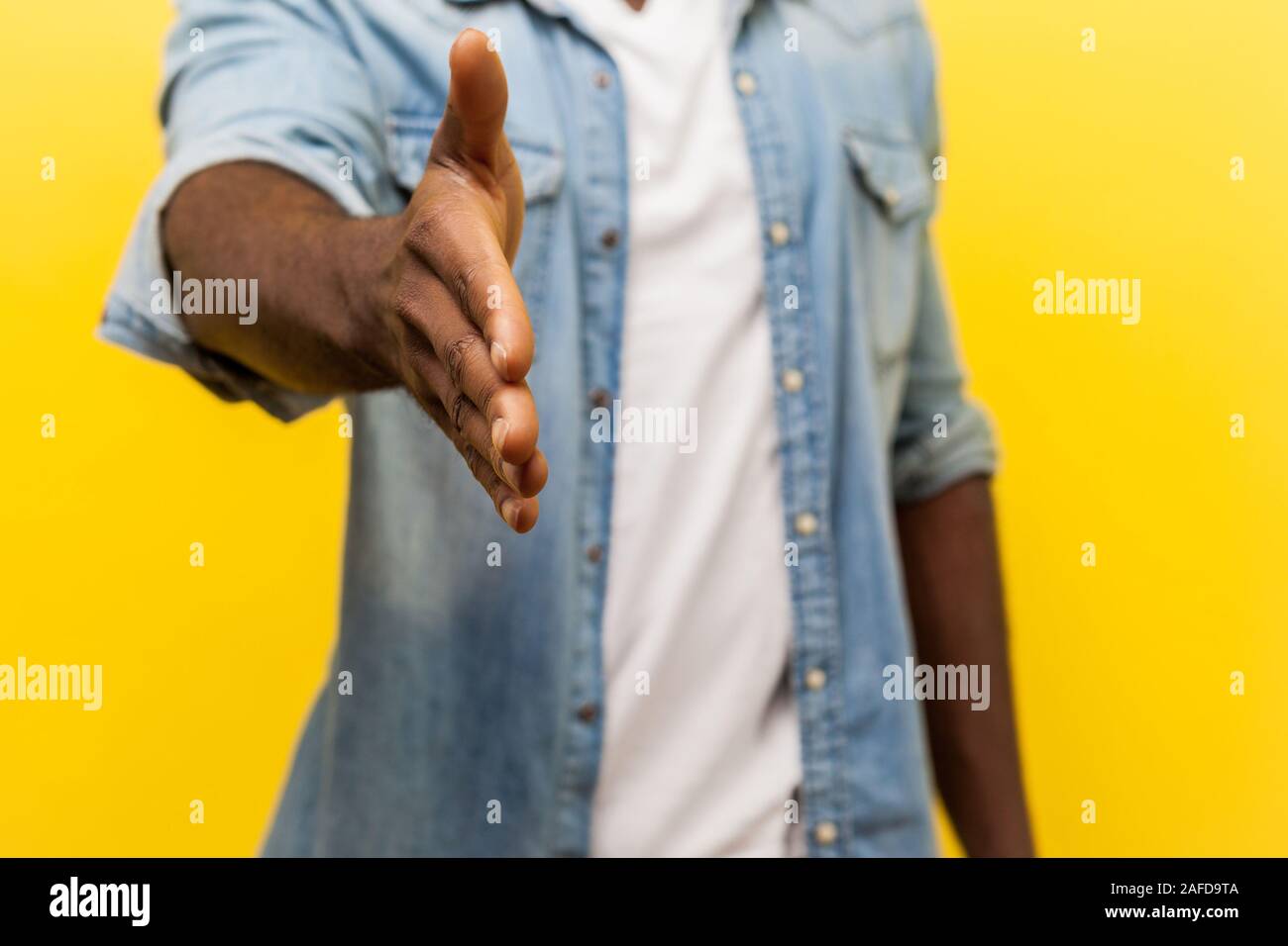 Ritratto di uomo in denim Camicia casual con arrotolato manicotti offrendo la mano per stretta di mano, conoscere nuove persone o incontro al colloquio di lavoro, salutare Foto Stock