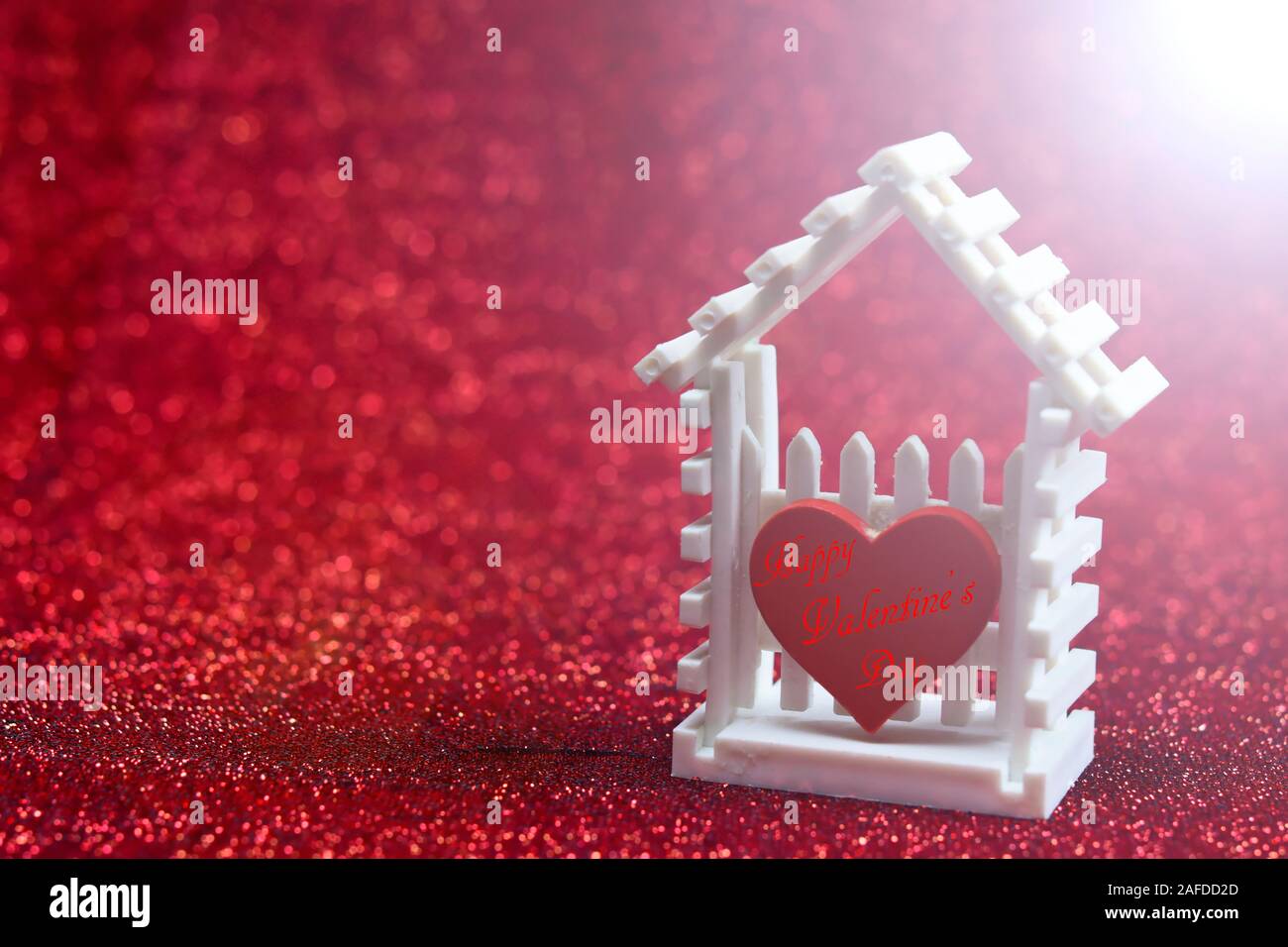 Soft sfocato di little white house e cuore rosso contro il bruciatore a fiamma viva luce sul rosso sfondo bokeh di fondo per il vostro design pattern o il vostro concetto di san valentino Foto Stock