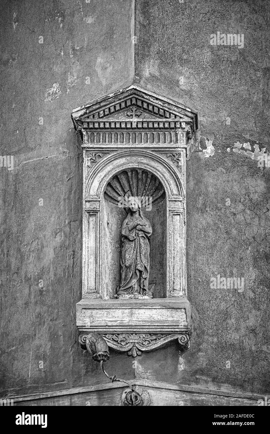 Un grungy la modifica di una piccola statua nicchia della Vergine Maria tenendo in braccio Gesù Bambino sull'angolo di un edificio in Roma, Italia Foto Stock