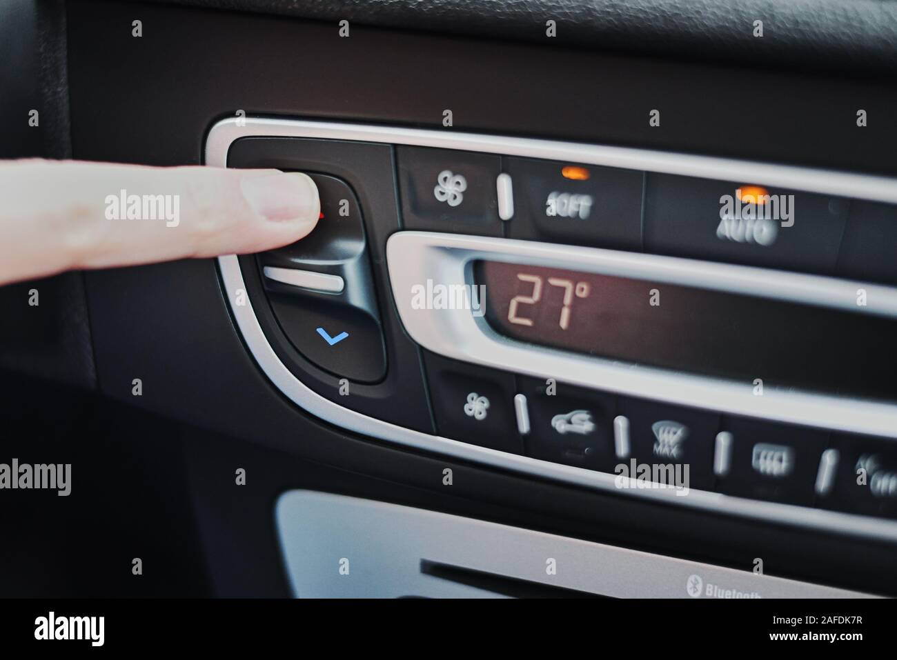 Donna mano impostare la temperatura sul condizionatore aria pannello in auto. Quadro di comando della climatizzazione Foto Stock