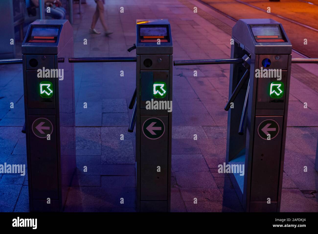 Tre i tornelli di una strada dalla stazione dei tram di notte di attesa per pochi passeggeri, nelle luci brillanti. Foto Stock
