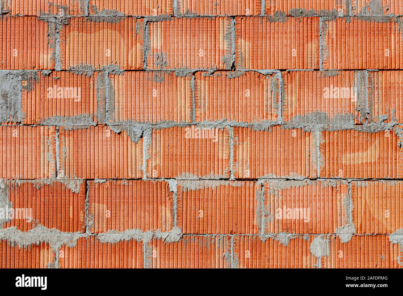Masoned parete fatta di colore rosso/arancione di mattoni e malta. Foto Stock