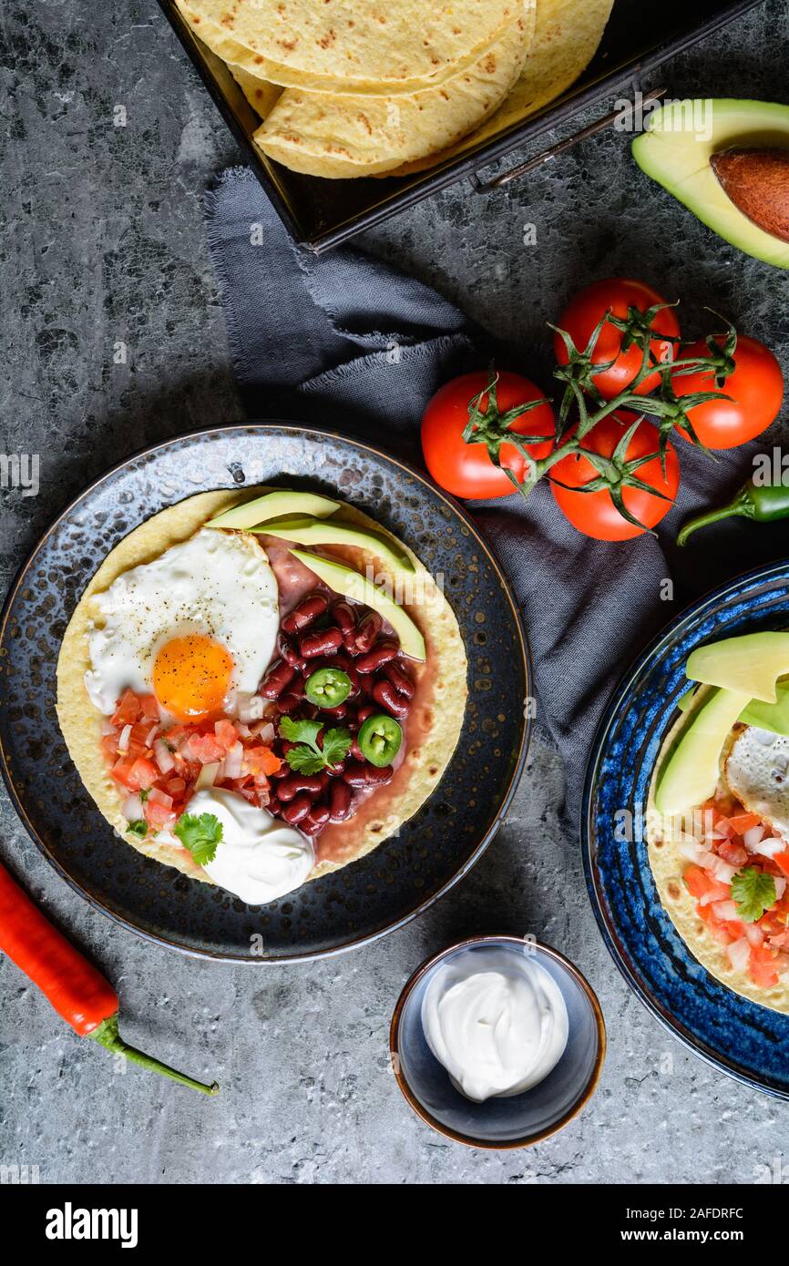 Deliziosa Huevos Rancheros Tostadas, colazione messicana consistente di tortilla tostato, pomodoro tagliato a pezzetti e la cipolla, jalapeno e fagiolo mash, guarnita con f Foto Stock