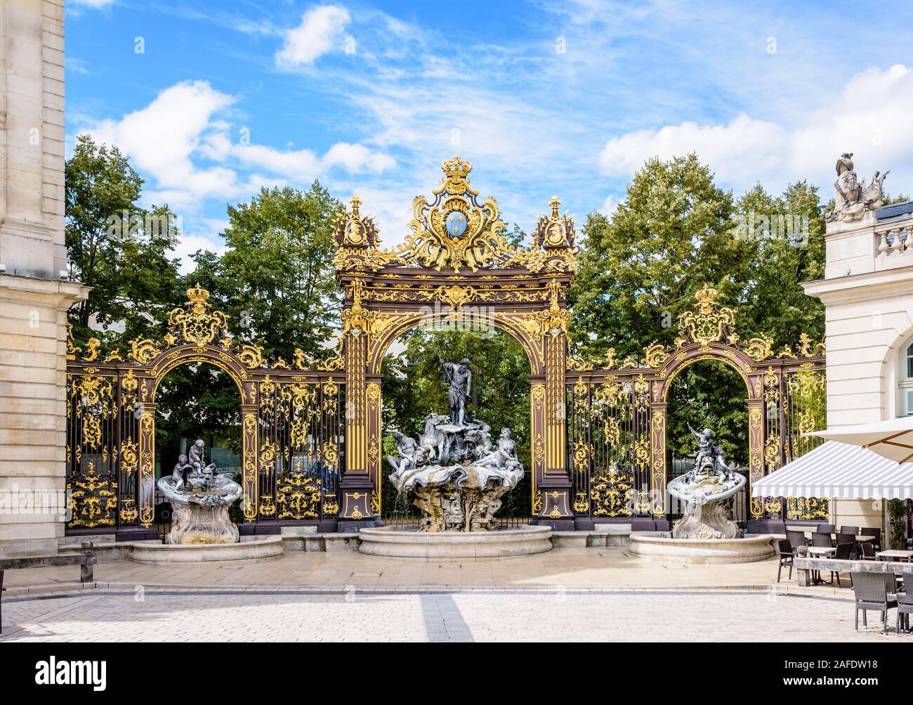 La fontana di Nettuno in stile rococo e il portico dorato in ferro battuto nell'angolo nord-ovest di piazza Stanislas a Nancy, Francia. Foto Stock