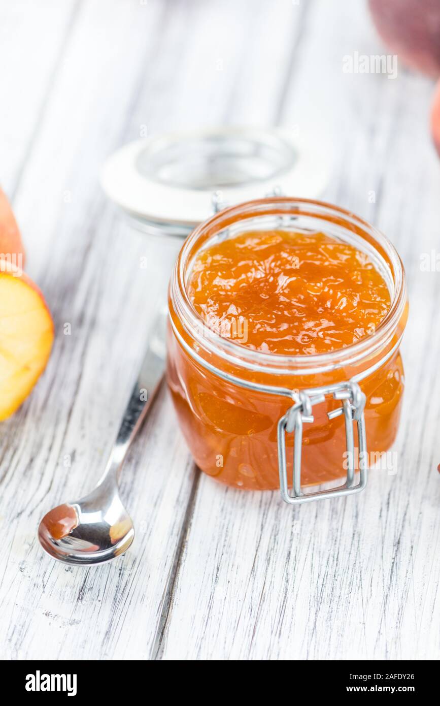 Tavolo in legno con confettura di pesche (messa a fuoco selettiva; close-up shot) Foto Stock