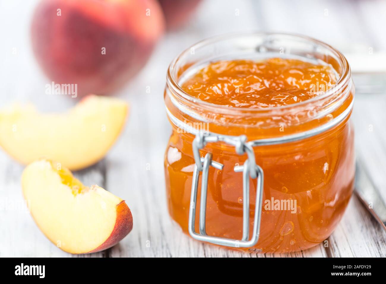 Confettura di pesche (messa a fuoco selettiva) su un vecchio tavolo di legno (close-up shot) Foto Stock