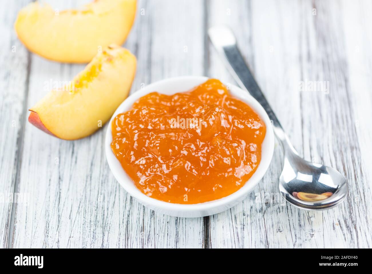 Confettura di pesche (messa a fuoco selettiva) su un vecchio tavolo di legno (close-up shot) Foto Stock